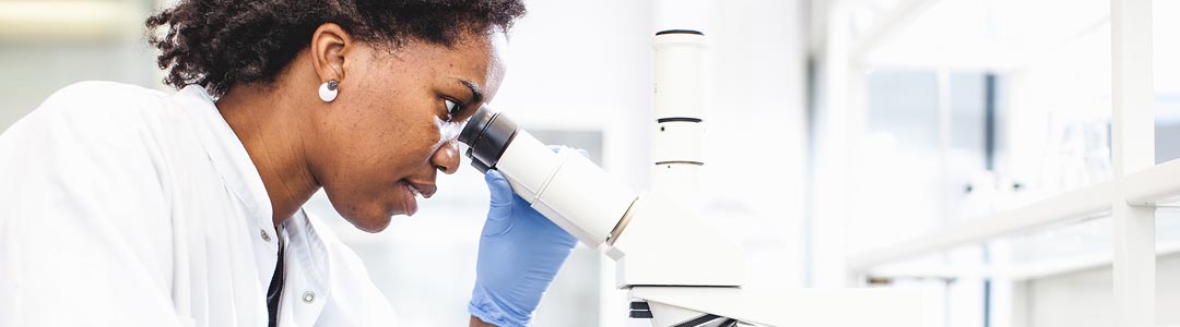 researcher looking through a microscope